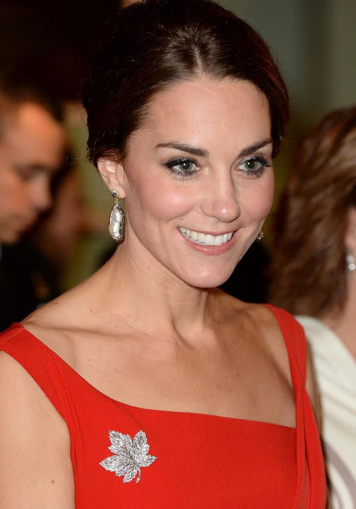 Kate Middleton, Duchess of Cambridge, shines in a red Preen by Thornton Bregazzi "Finella" dress, accessorized with Queen Elizabeth's iconic maple leaf brooch