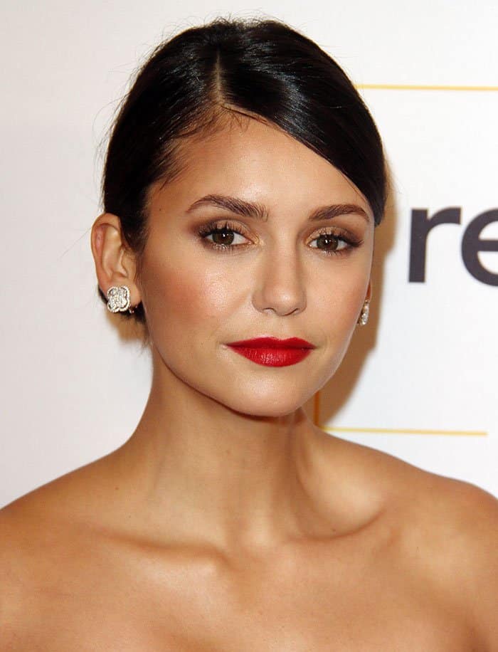 Nina Dobrev elevated her glam with a sleek updo, glowing skin, and a bold red lip that perfectly complemented her modern strapless look