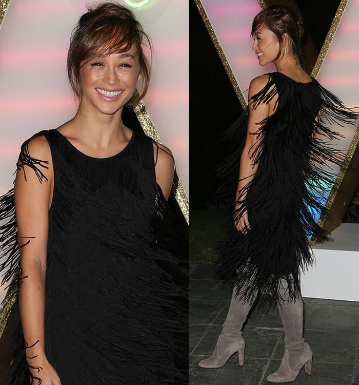 Cara Santana playfully twirls in her black fringe dress, creating a mesmerizing movement, perfectly paired with gray Stuart Weitzman thigh-high boots