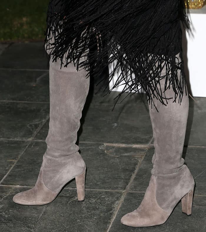 Cara Santana grounds her look with a pair of stunning gray Stuart Weitzman thigh-high suede boots, providing a perfect balance to the playful movement of her dress