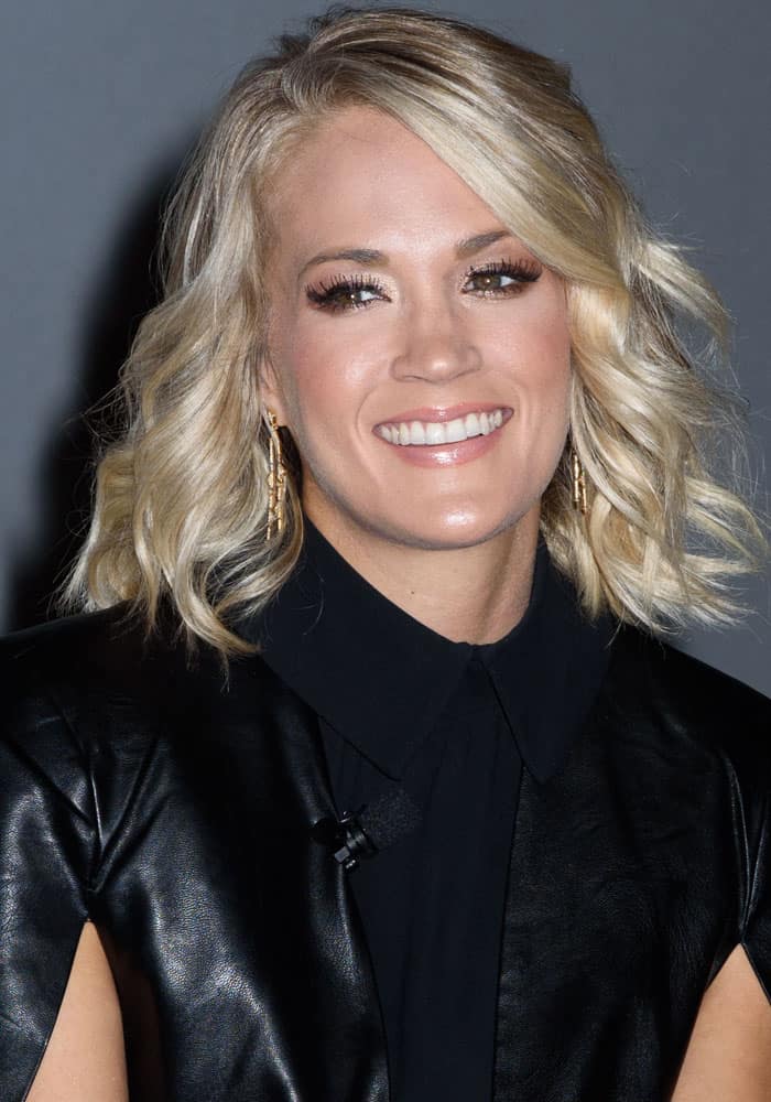 Carrie Underwood exudes edgy elegance in a sleek black leather top paired with soft curls and statement earrings