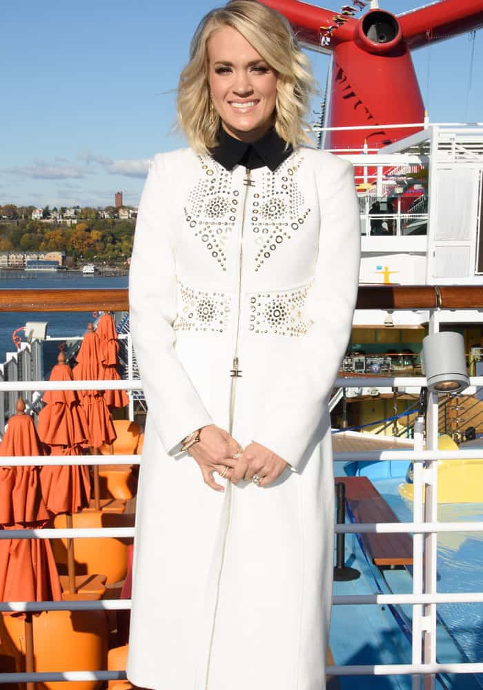 Carrie Underwood brightens up in a chic white studded coat, layered over her sleek black ensemble, while aboard the Carnival Vista