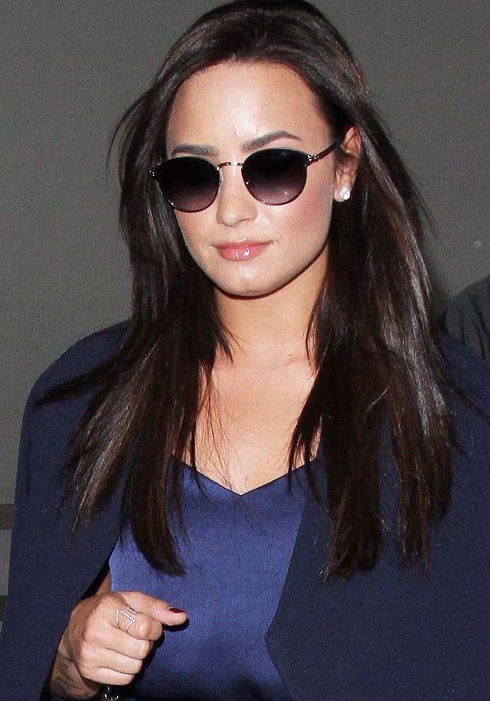 Demi Lovato exudes confidence in a chic navy ensemble paired with stylish sunglasses while arriving at LAX
