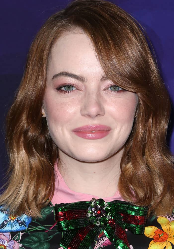 Emma Stone wore her auburn hair in soft, glossy waves, accentuating her green eyes with rose-toned eyeshadow and matching pink lipstick for a fresh, romantic beauty look