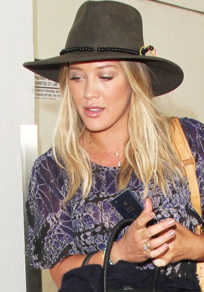 Hilary Duff keeps it casual yet stylish at the airport, pairing a wide-brimmed hat with a patterned top and understated accessories