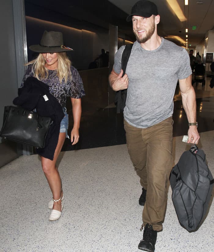 Hilary Duff and Jason Walsh spotted at LAX, with Hilary in a casual-chic outfit featuring a wide-brimmed hat, denim shorts, and Valentino 'Rockstud' espadrilles