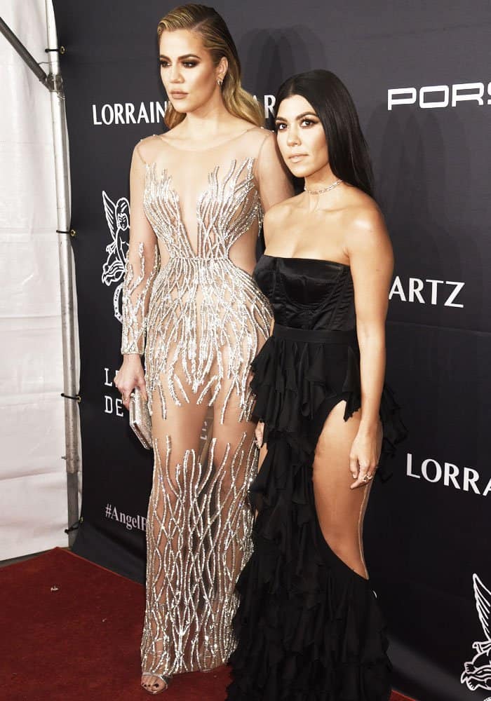Khloé Kardashian and Kourtney Kardashian stun on the red carpet, with Khloe in a dazzling sheer Yousef Aljasmi gown and Kourtney in a dramatic black ruffled dress with a thigh-high slit
