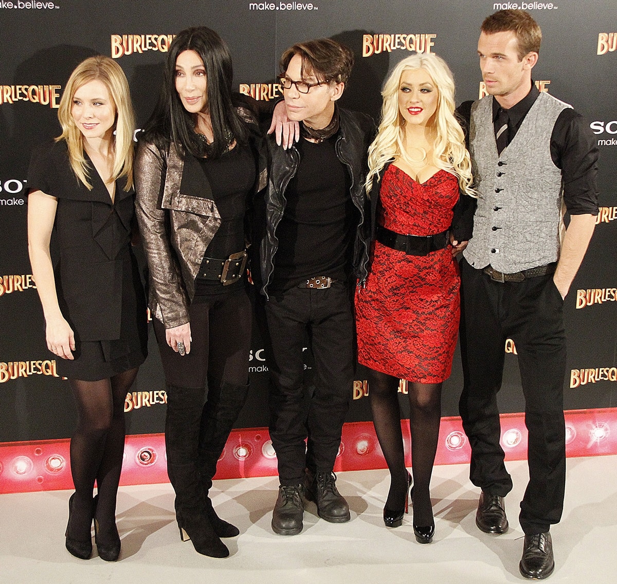 Kristen Bell, Cher, director Steven Antin, Christina Aguilera, and Cam Gigandet strike a pose at the Burlesque photocall in Madrid on December 9, 2010—each making a footwear statement, from Kristen’s classic black pumps to Cher’s bold knee-high boots and Christina’s patent platform heels
