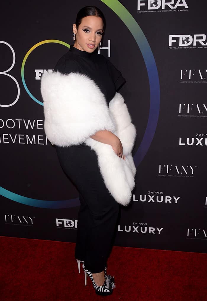 Dascha Polanco stuns in a black jumpsuit with a white fur stole and zebra-striped Charlotte Olympia heels at the 30th Footwear News Achievement Awards