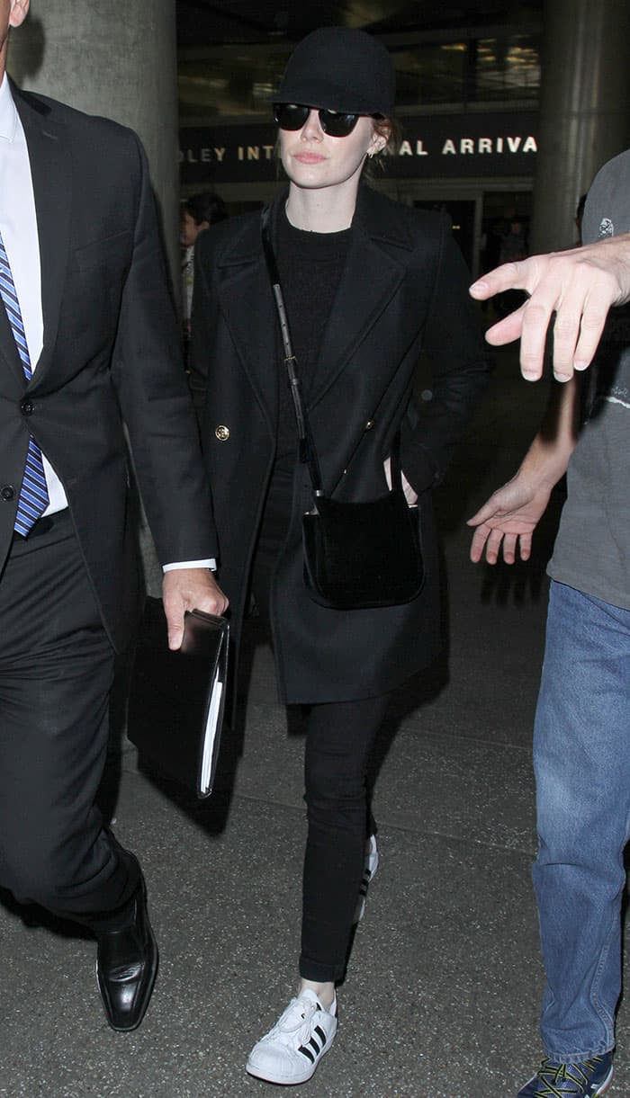 Emma Stone’s Adidas "Superstar" sneakers, featuring black stripes, add a subtle contrast to her monochromatic look