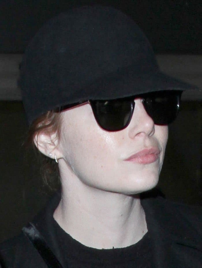 Emma Stone goes incognito at LAX with minimal makeup, a sleek riding cap, and classic Ray-Ban sunglasses
