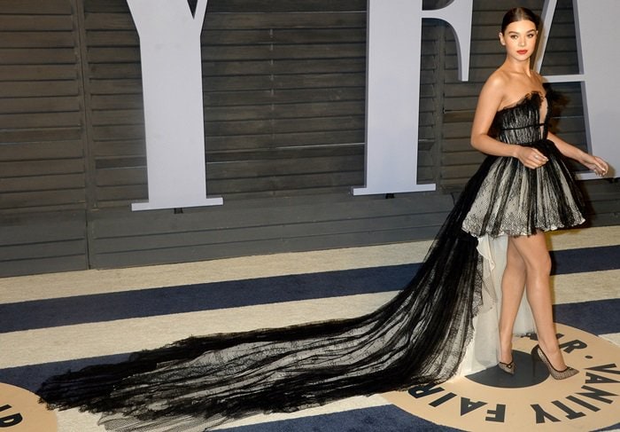 The gown’s sweeping black tulle train creates a dramatic silhouette while Hailee Steinfeld’s delicate lace pumps keep the exposed front of the look visually light