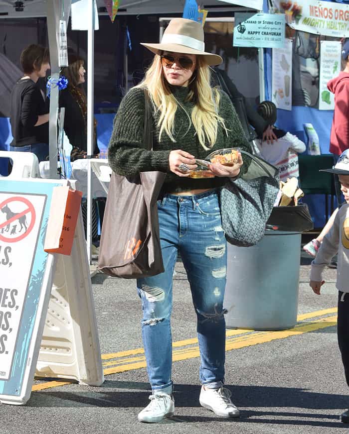 Hilary Duff, looking chic and casual, pairs a green knit sweater and distressed jeans with Golden Goose sneakers