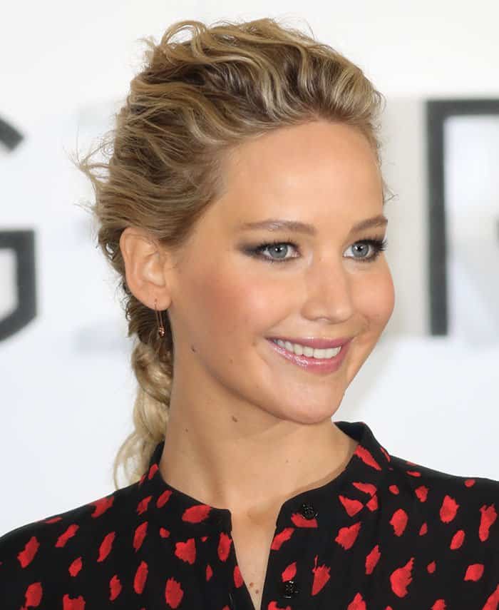A close-up highlights Lawrence’s polished beauty look, with a braided ponytail and minimal jewelry allowing the graphic print of her Proenza Schouler dress to take center stage