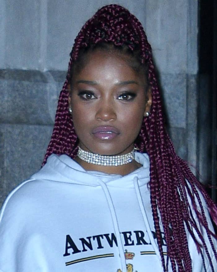 Keke Palmer rocks bold magenta braids, a sparkling crystal choker, and striking makeup with dark eyeliner and glossy pale purple lips