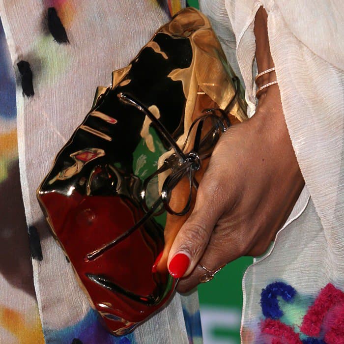 Kelly Rowland accessorized her look with a striking gold mirrored clutch and completed it with a classic red manicure