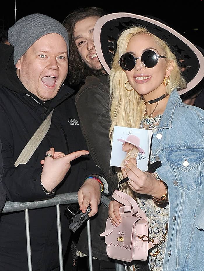 Lady Gaga happily signs autographs for fans while flaunting her pink Joanne handbag and star-adorned wide-brimmed hat outside Tape Nightclub in London