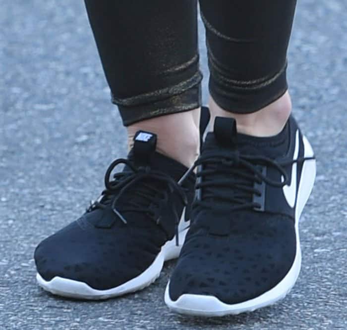 Close-up of Hilary Duff’s Nike “Juvenate” sneakers, featuring a sleek black mesh upper and white rubber outsole for a trendy, sporty look