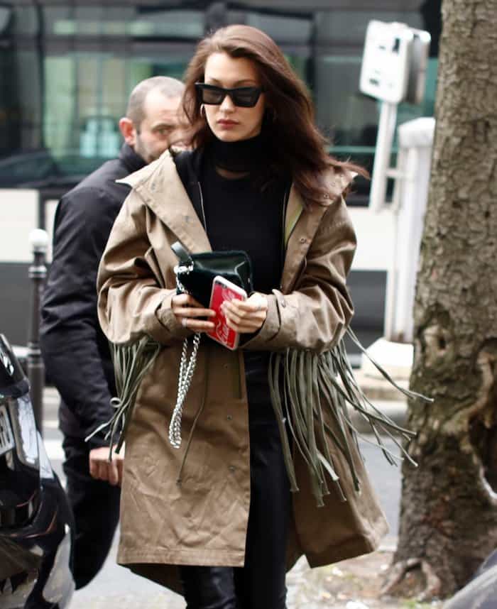 Bella Hadid shopping in Paris wearing Celine sunglasses, an oversized fringed trench coat, and carrying a Dior Diorama Club bag