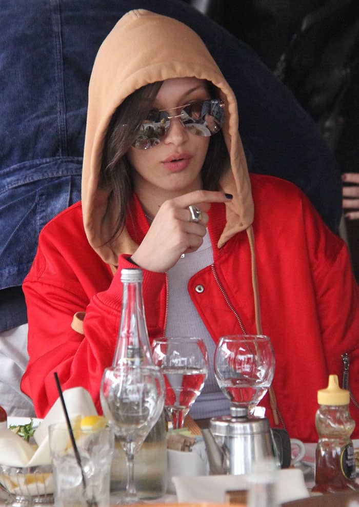 Bella Hadid enjoys a casual lunch at Il Pastaio, keeping a low profile with her hood up and Quay Playa sunglasses on