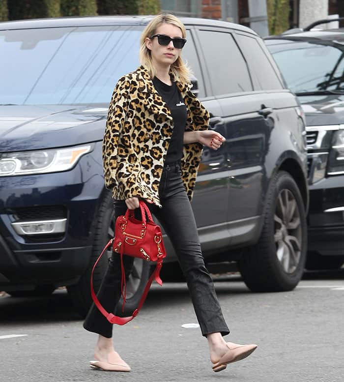 Emma Roberts steps out in style at A.P.C., wearing Paige leather pants, Nicholas Kirkwood flat mules, a Coach leopard-print peacoat, and accessorizing with a Balenciaga mini satchel and Warby Parker sunglasses
