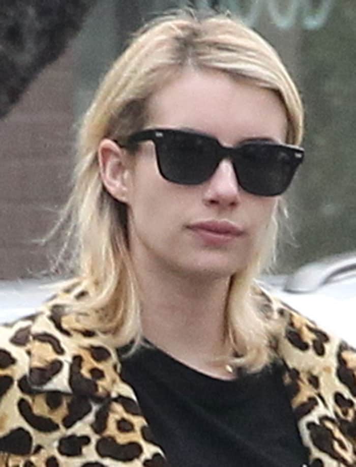 Emma Roberts sports classic black sunglasses and a relaxed, shoulder-length hairstyle