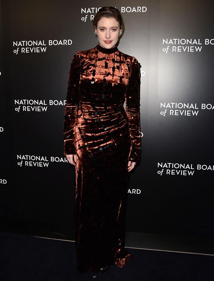 Greta Gerwig shows how to elevate a winter evening look with a brown velvet dress featuring subtle embellishments, paired with sleek hair and minimal accessories for effortless sophistication