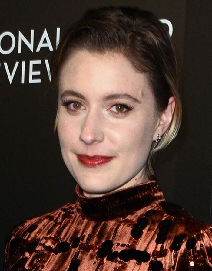 Greta Gerwig keeps it classy with slicked-back hair, sultry eye makeup, minimal jewelry, and bold red lipstick