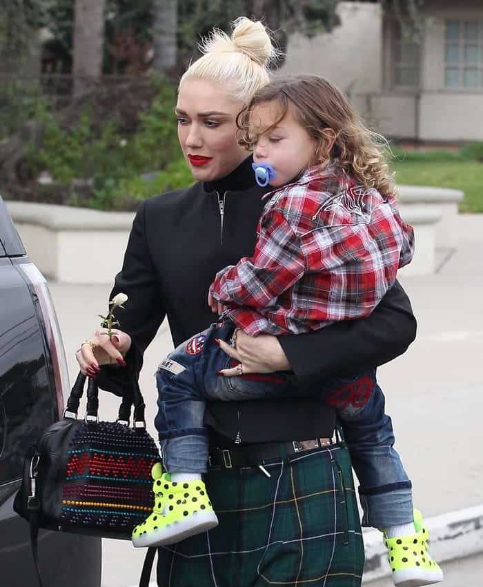 Apollo Rossdale adds a pop of color to the outing in a red plaid shirt, patch-detailed jeans, and bright neon yellow polka-dot high-top sneakers