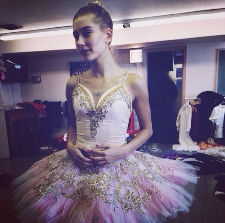 Hailey Bieber wears an elaborately embellished pink-and-gold tutu backstage during her years as a young ballet dancer