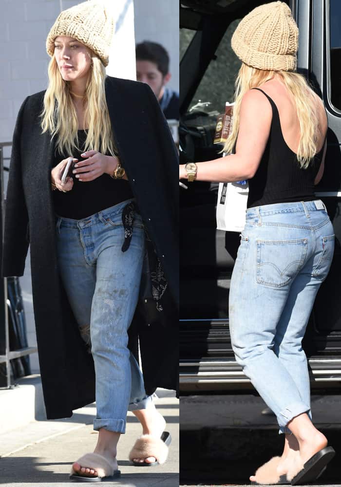 Hilary Duff enjoys the California sunshine in a laid-back yet stylish outfit, pairing a cozy black trench with a ribbed bodysuit, cuffed jeans, a chunky knit beanie, and Givenchy fur slides that add a touch of casual luxury to her relaxed look