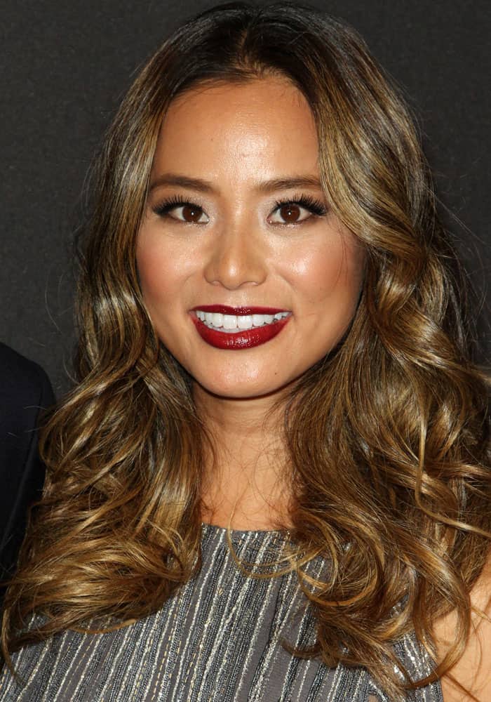Jamie Chung has voluminous brown hair with subtle highlights, rich brown eyes, and bold dark red lips