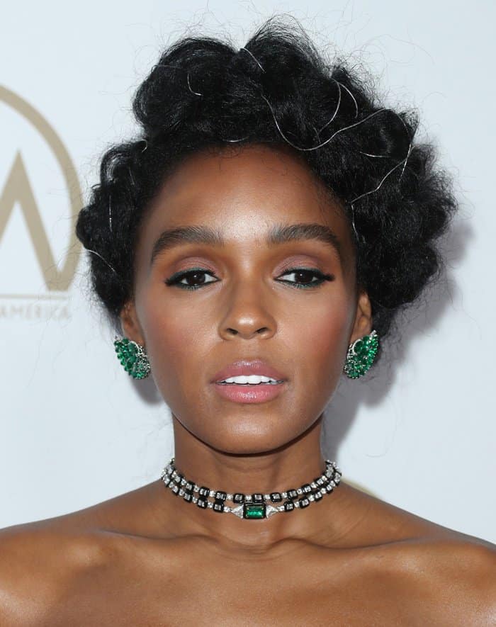 Janelle Monáe’s natural hair updo, accented with silver details, and her flawless makeup featuring emerald-toned eyeliner, perfectly highlighted her bold and glamorous style
