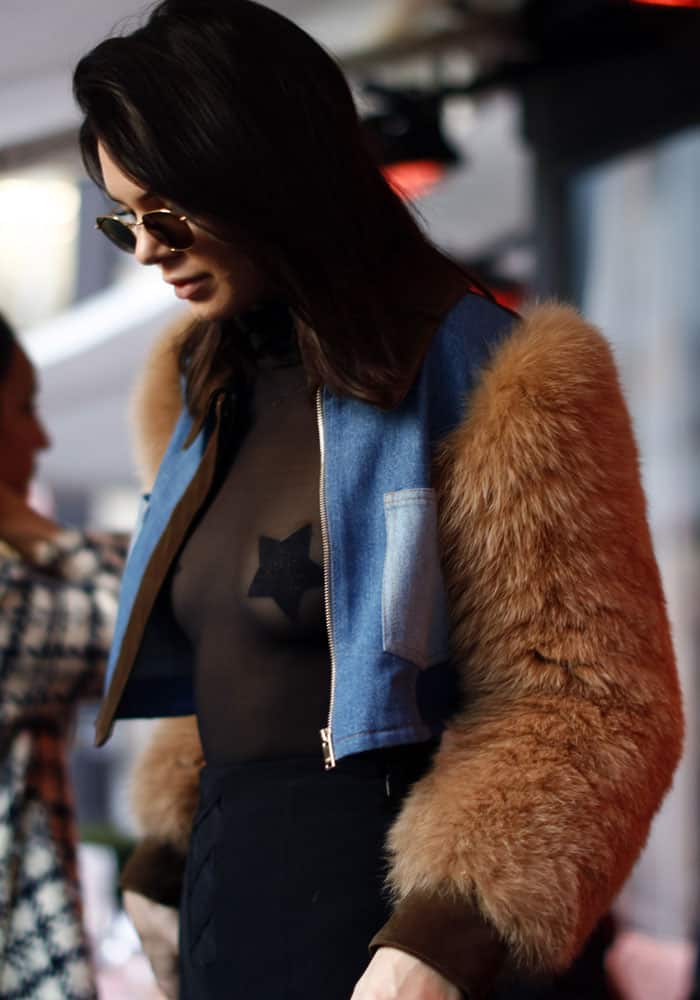 Seen from above, her outfit balances a fur-trimmed denim jacket with a sheer star-detailed top, reinforcing the contrast-driven styling that defined the look