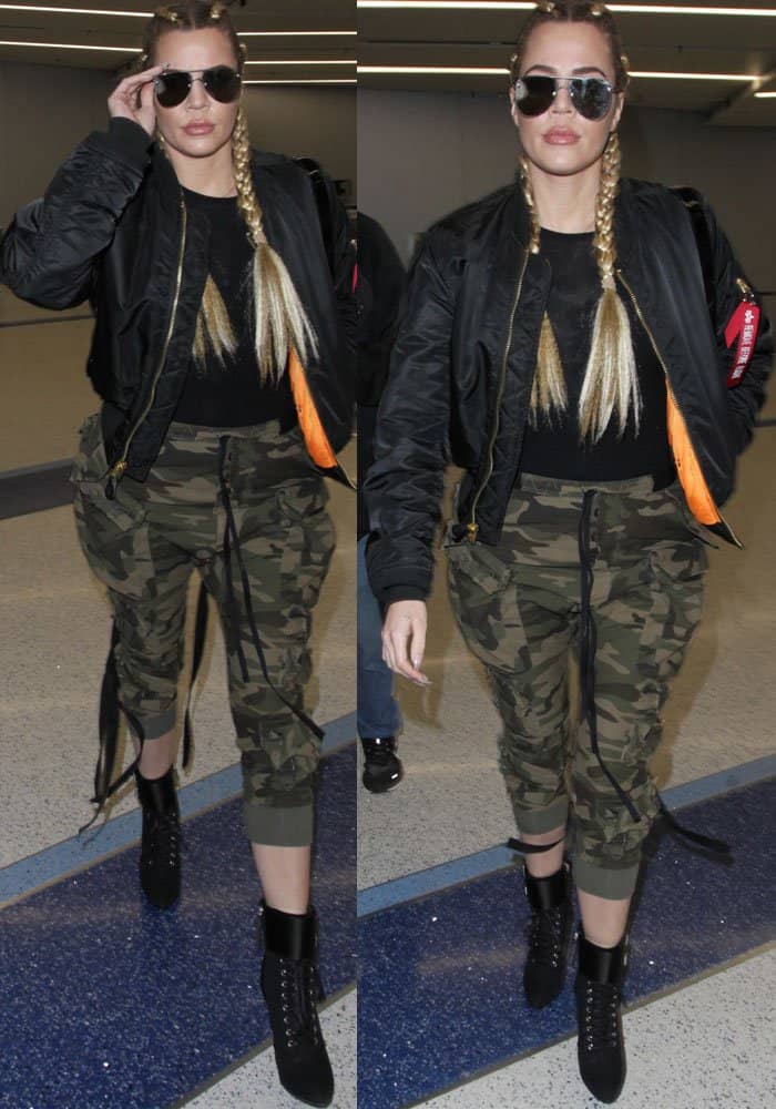 To recreate Khloé Kardashian's edgy airport look, pair a black fitted top with loose camouflage joggers, a bomber jacket, and lace-up black boots, finishing with aviator sunglasses for a bold touch