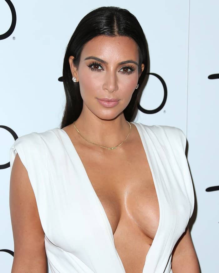 Kim Kardashian stuns in a daring white gown with a plunging neckline, showcasing her flawless makeup and sleek, straight hair