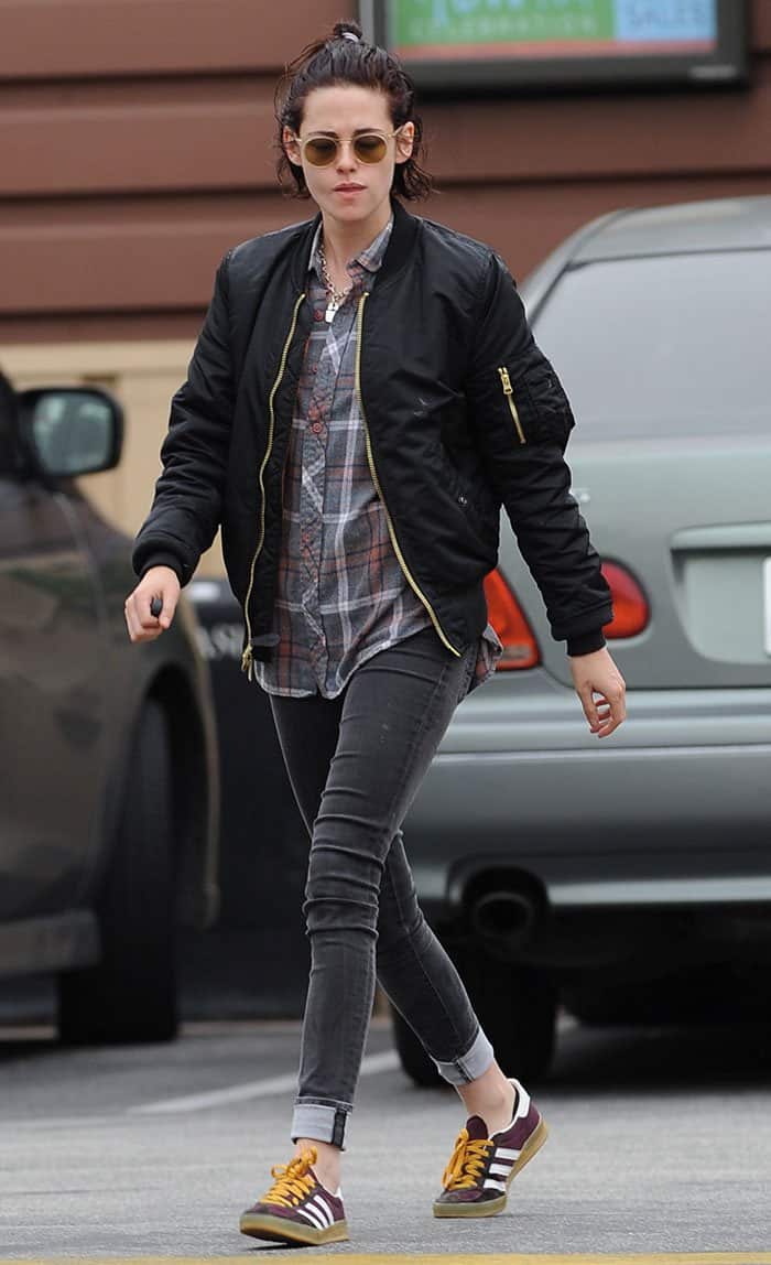 Kristen Stewart was spotted in Los Angeles in a laid-back look, pairing her black Saint Laurent bomber jacket with a plaid shirt, cuffed skinny jeans, and maroon Adidas Gazelles with bold yellow laces