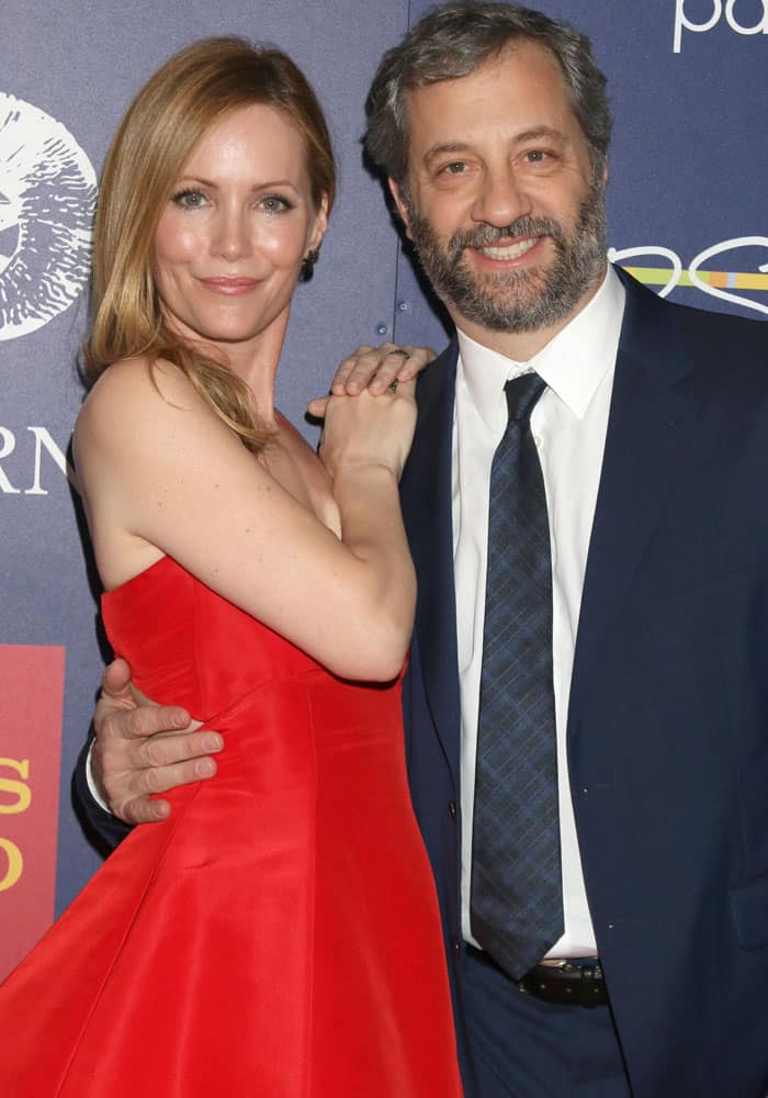 Leslie Mann radiates elegance in a vibrant red fit-and-flare dress, posing alongside her husband, Judd Apatow, who complements her look with a classic navy suit and tie