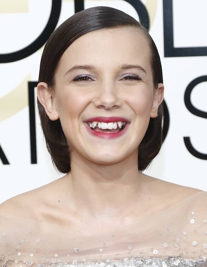 Millie Bobby Brown flashes a joyful smile at the 2017 Golden Globes, showing off her youthful charm and signature gap-toothed grin during her early Stranger Things breakout years