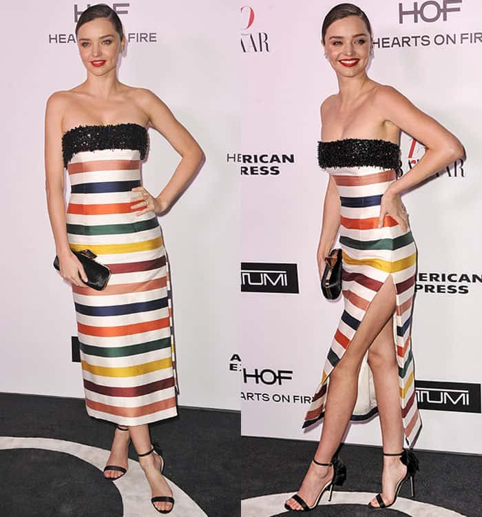 Miranda Kerr stuns in a strapless Carolina Herrera dress featuring vibrant horizontal stripes in shades of red, orange, yellow, green, blue, and white, accented by a black sequin neckline and a thigh-high slit