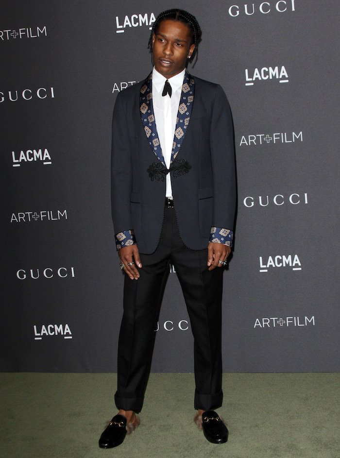 A$AP Rocky exudes bold sophistication in a tailored Gucci suit, accented with intricate embroidered cuffs and paired with iconic fur-lined Gucci Princetown loafers