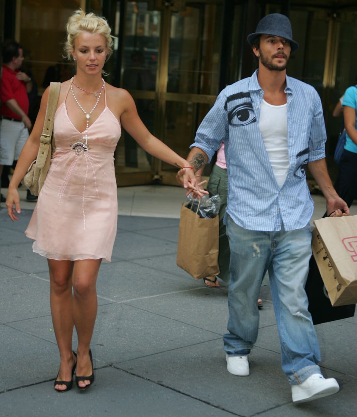 Britney Spears steps out in a blush pink halter mini dress and classic black peep-toe heels while holding hands with then-husband Kevin Federline, known for his laid-back streetwear and bold printed shirt