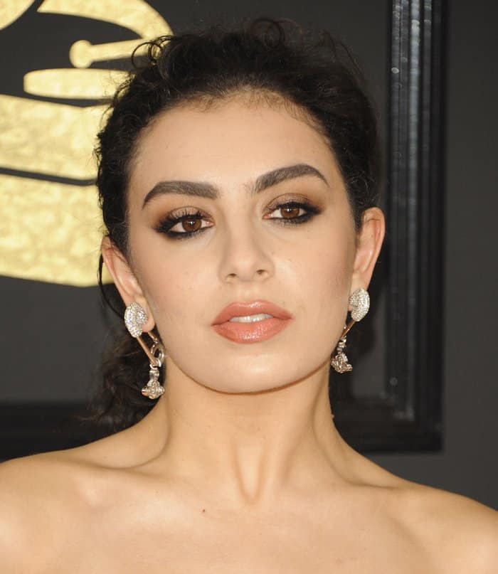 Charli XCX completed her red carpet look with a voluminous textured updo, dramatic smoky eye makeup, sculpted brows, and a soft nude lip, perfectly balancing edgy glamour and sophistication