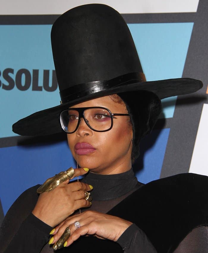 Erykah Badu's look is elevated by her intricate gold full-finger rings, striking yellow nails, and delicate facial jewelry