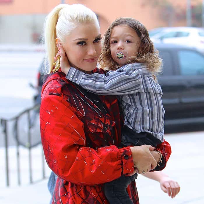 Gwen Stefani carries son Apollo as she arrives at St. Brendan Catholic Church, pairing her platinum ponytail with a striking red Moschino ensemble