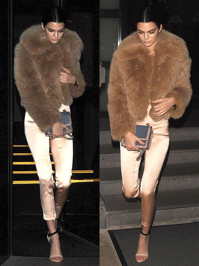 Kendall Jenner elevates neutral tones with silk trousers, a fur jacket, and La Perla’s black-and-nude ankle-strap sandals, accessorized with a bold blue-and-pink clutch