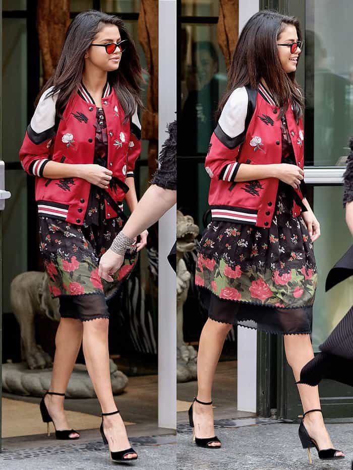 Selena Gomez rocks a spring-ready Coach floral dress paired with a matching embroidered varsity jacket and elegant Givenchy "Matilda" sandals for a chic yet playful NYC outing