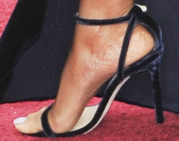 Taraji P. Henson’s foot peeks from beneath the velvet train, revealing her black Jimmy Choo “Minny” sandals with delicate ankle straps, slim stiletto heels, and minimalist barely-there design that perfectly complements the gown’s sleek, Old Hollywood silhouette