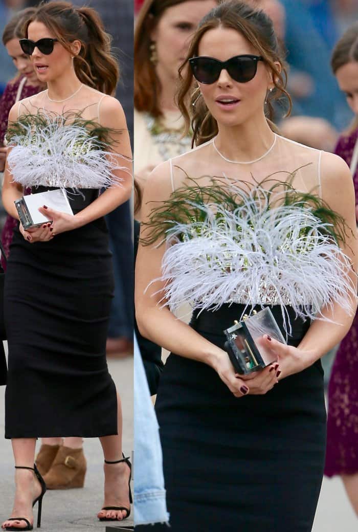 Kate Beckinsale elevates her chic daytime look with oversized black cat-eye sunglasses and a sleek acrylic clutch