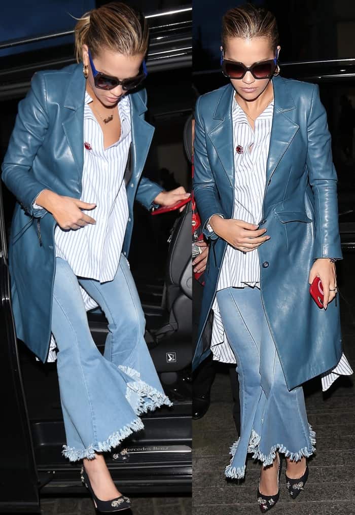 Rita Ora steps out in a striking ensemble featuring a blue leather coat, a striped hi-lo shirt, frayed flare jeans, and crystal-embellished Jimmy Choo 'Romy' pumps for a bold yet chic look
